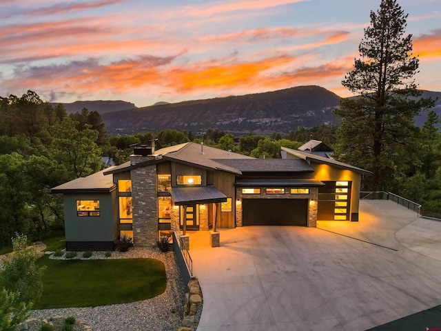2161 Scout Ridge Rd, Durango, CO 81301 - view of front facade with stone siding, a garage, a mountain view, driveway, and a chimney