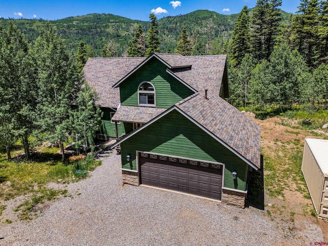 261 Aspen Dr, Durango, CO 81301 - rustic home with stone siding, a forest view, gravel driveway, and a garage