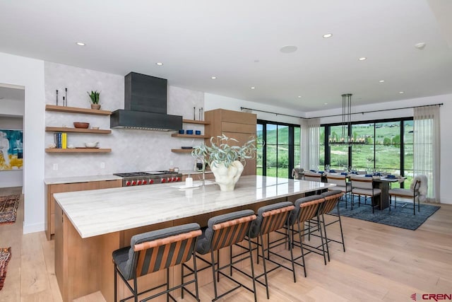 33 Aperture Ln, Crested Butte, CO 81224 - kitchen featuring wall chimney exhaust hood, open shelves, light wood-style flooring, a large island, and backsplash