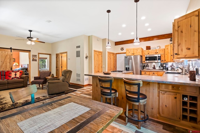 17401 County Road 501, Bayfield, CO 81122 - kitchen with stainless steel appliances, a peninsula, ceiling fan, a barn door, and light wood-style flooring