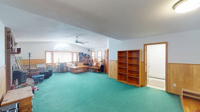 100 Paonia Ave, Paonia, CO 81428 - carpeted living room featuring vaulted ceiling, wainscoting, a ceiling fan, wooden walls, and a baseboard heating unit