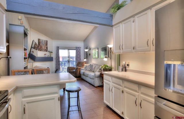 2920 Holly Ave Unit 104, Durango, CO 81301 - kitchen with stainless steel fridge with ice dispenser, vaulted ceiling, light countertops, white cabinetry, and a kitchen breakfast bar