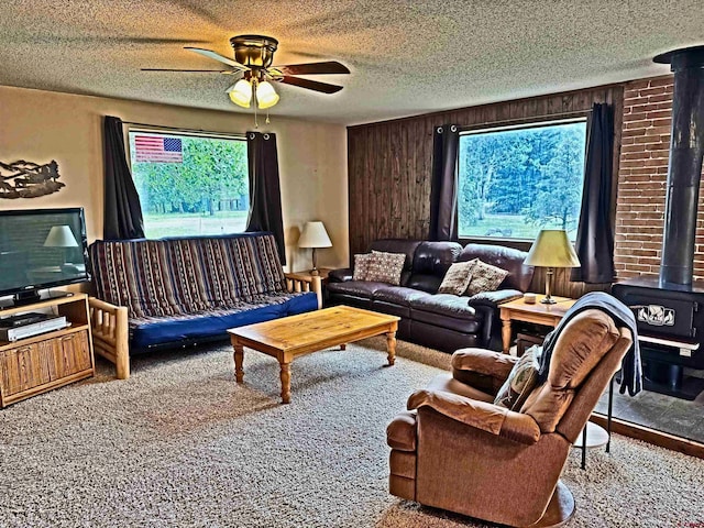 152 Conifer Dr, South Fork, CO 81154 - living room with ceiling fan, a wood stove, a textured ceiling, carpet, and wood walls