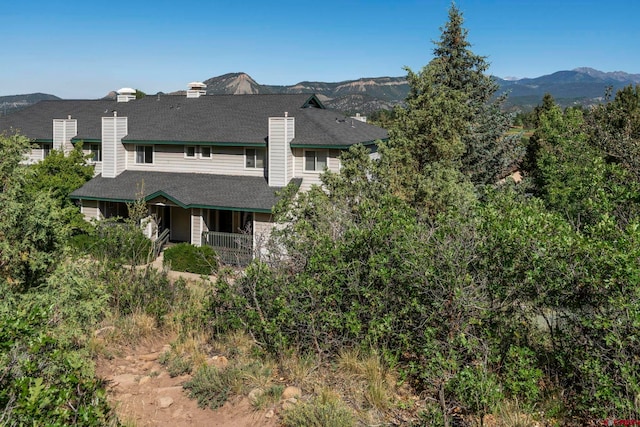 1100 Goeglein Gulch Rd Unit 171, Durango, CO 81301 - view of front of property featuring a chimney, a shingled roof, a mountain view, and covered porch
