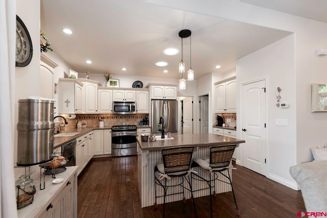 1734 Dry Creek Cir, Delta, CO 81416 - kitchen with stainless steel appliances, tasteful backsplash, a kitchen breakfast bar, dark wood-style flooring, and hanging light fixtures