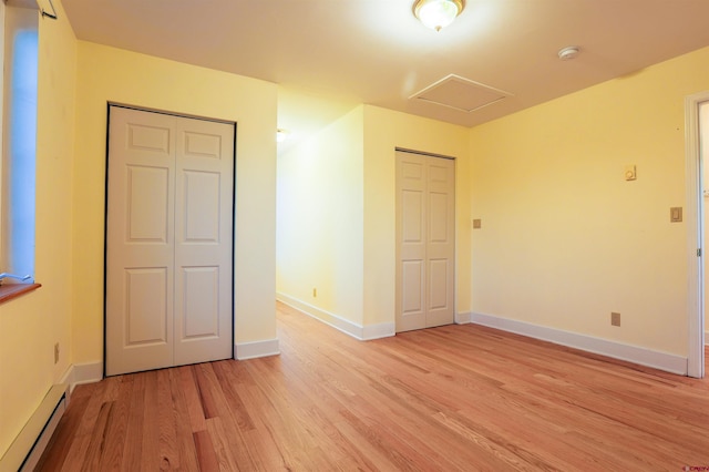825 County Road 17, Gunnison, CO 81230 - unfurnished bedroom featuring light wood-style floors, attic access, a baseboard radiator, and two closets