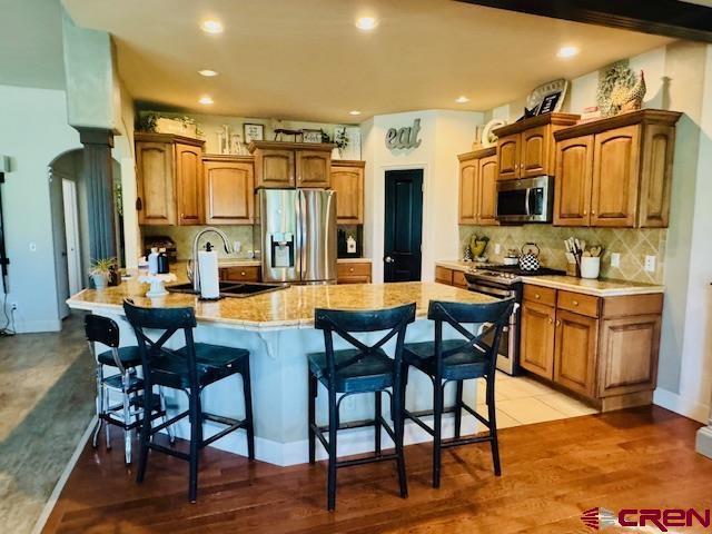 1490 SE Fairway Dr, Cedaredge, CO 81413 - kitchen featuring appliances with stainless steel finishes, a kitchen breakfast bar, brown cabinets, tasteful backsplash, and recessed lighting
