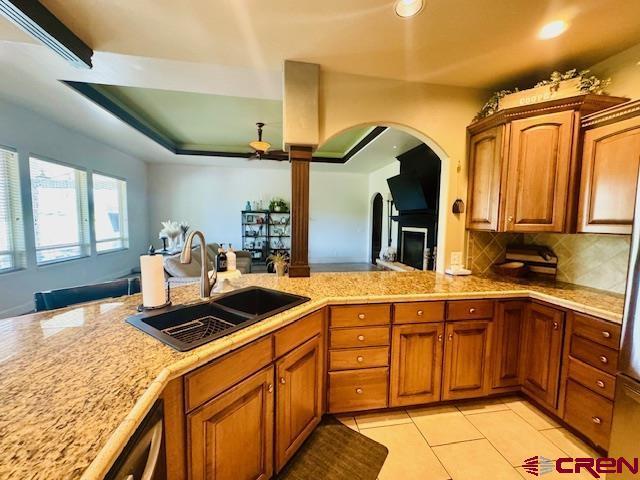 1490 SE Fairway Dr, Cedaredge, CO 81413 - kitchen with brown cabinets, arched walkways, tasteful backsplash, light tile patterned flooring, and recessed lighting