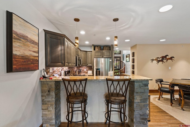 73 S Tamarron Dr Unit 822, Durango, CO 81301 - kitchen featuring stainless steel appliances, a peninsula, light stone counters, wood finished floors, and a breakfast bar