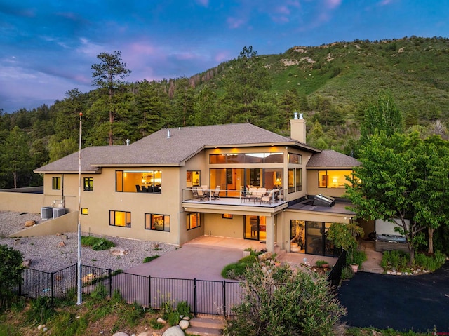 570 Jenkins Ranch Rd, Durango, CO 81301 - back of house with stucco siding, a chimney, driveway, a patio area, and a forest view