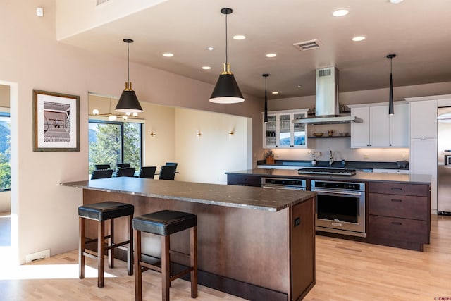 570 Jenkins Ranch Rd, Durango, CO 81301 - kitchen featuring stainless steel appliances, island range hood, light wood-style flooring, dark countertops, and recessed lighting