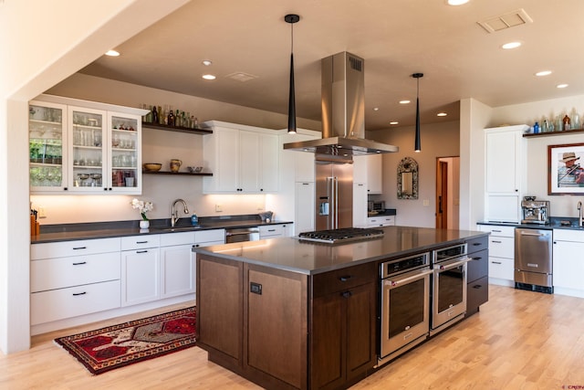 570 Jenkins Ranch Rd, Durango, CO 81301 - kitchen featuring island exhaust hood, dark countertops, appliances with stainless steel finishes, light wood finished floors, and open shelves