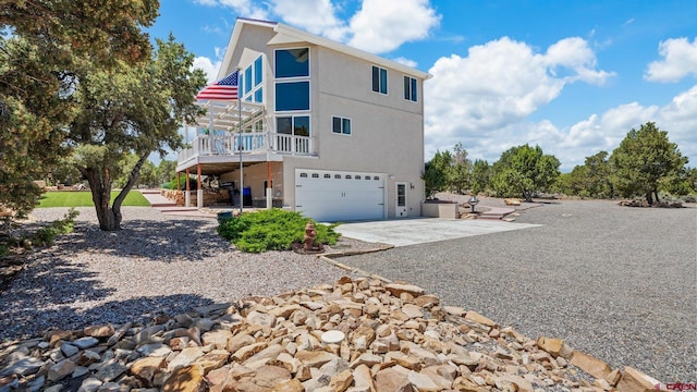 61850 V62 Trl, Montrose, CO 81403 - rear view of property with stucco siding, an attached garage, concrete driveway, and a wooden deck