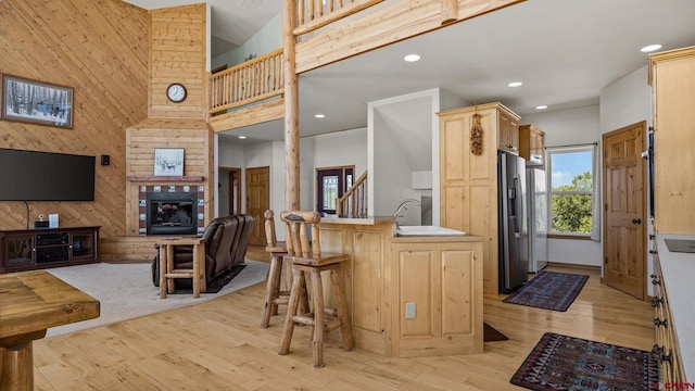 61850 V62 Trl, Montrose, CO 81403 - kitchen with light brown cabinets, wooden walls, stainless steel refrigerator with ice dispenser, light wood-style flooring, and a high ceiling