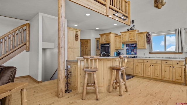 61850 V62 Trl, Montrose, CO 81403 - kitchen featuring light brown cabinets, oven, light countertops, light wood-style flooring, and a kitchen bar