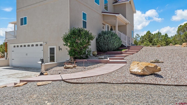 61850 V62 Trl, Montrose, CO 81403 - view of side of property with concrete driveway, a garage, stucco siding, and stairs