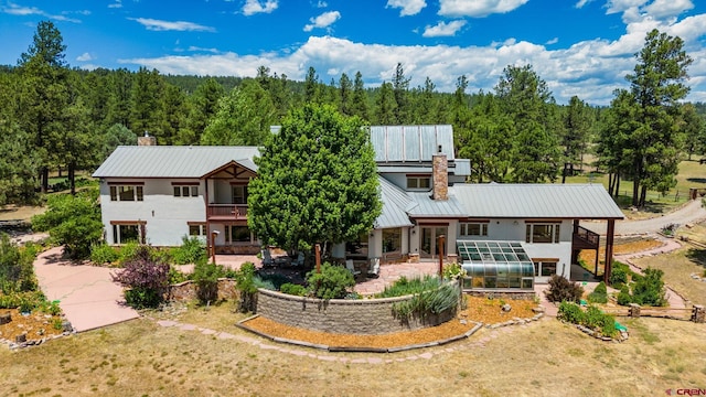 2415 Echo Canyon Ranch Ln, Pagosa Springs, CO 81147 - view of front facade with a greenhouse, a chimney, a view of trees, and a balcony