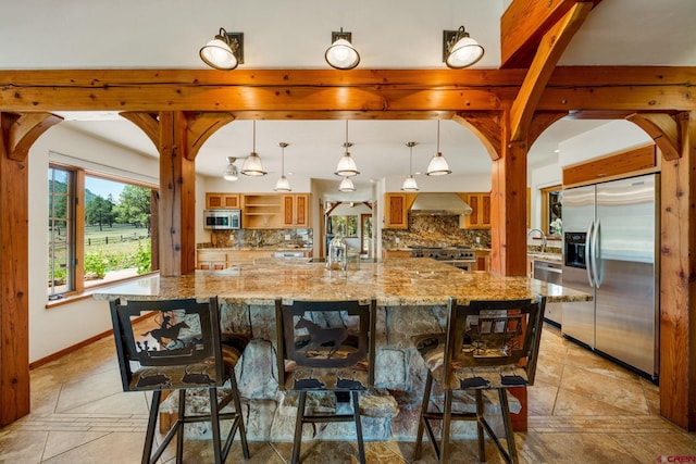2415 Echo Canyon Ranch Ln, Pagosa Springs, CO 81147 - kitchen featuring appliances with stainless steel finishes, tasteful backsplash, wall chimney exhaust hood, arched walkways, and a breakfast bar