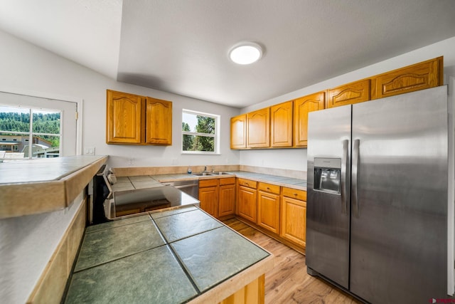 268 Forest Lakes Dr, Bayfield, CO 81122 - kitchen with stainless steel fridge with ice dispenser, light wood-style floors, tile countertops, and brown cabinets