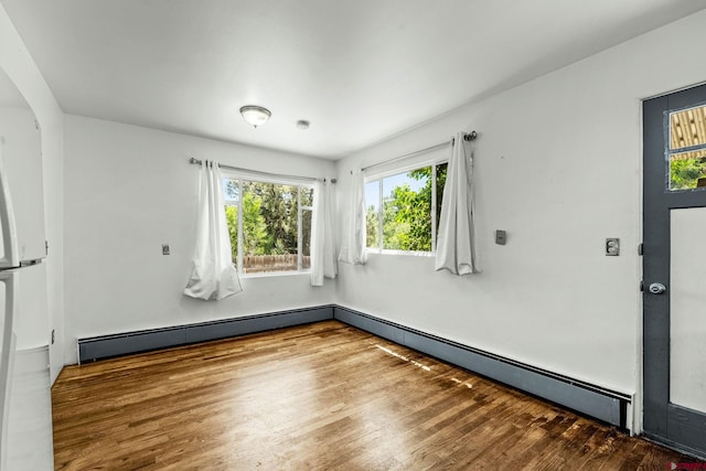 111 E 31st St, Durango, CO 81301 - unfurnished room with healthy amount of natural light, baseboard heating, wood finished floors, and arched walkways