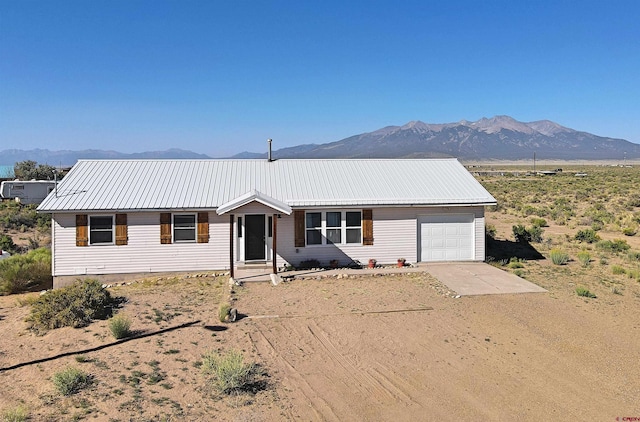 19029 Country Dr, Alamosa, CO 81101 - single story home with an attached garage, concrete driveway, a mountain view, and a metal roof