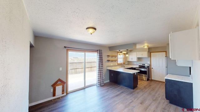 19029 Country Dr, Alamosa, CO 81101 - kitchen featuring stainless steel electric range oven, a peninsula, a textured ceiling, freestanding refrigerator, and light countertops