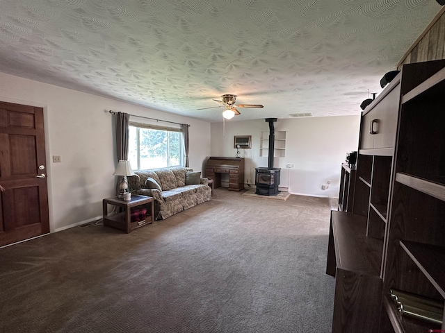 1885 Nichols Way, Montrose, CO 81401 - living area featuring a wood stove, a ceiling fan, dark carpet, and a textured ceiling