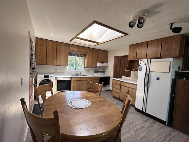 1885 Nichols Way, Montrose, CO 81401 - kitchen with white appliances, washer / clothes dryer, a skylight, light wood-type flooring, and light countertops