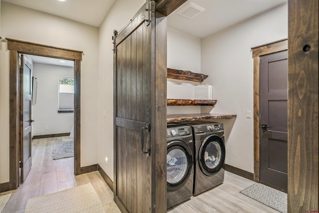 791 Antelope Ave, Pagosa Springs, CO 81147 - washroom with washing machine and dryer, a barn door, and light wood-style flooring