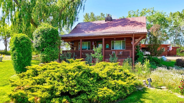 27126 Road R, Dolores, CO 81323 - view of front of house featuring log exterior, a metal roof, a chimney, and a porch