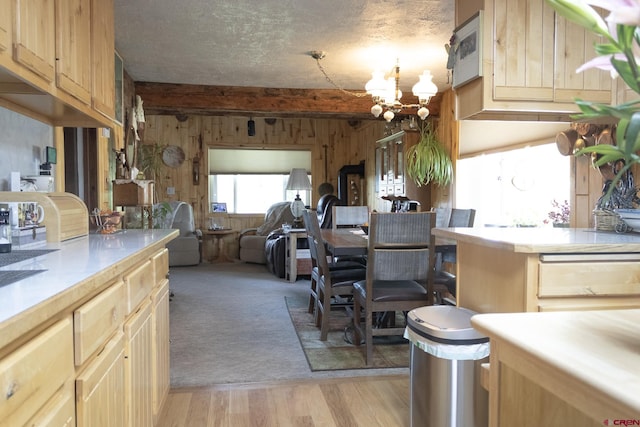 27126 Road R, Dolores, CO 81323 - kitchen with wood walls, a chandelier, light countertops, light brown cabinetry, and light wood-type flooring