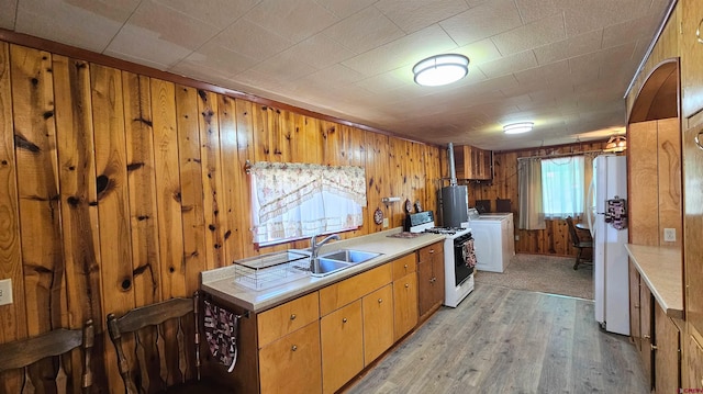 59 Willow St, South Fork, CO 81154 - kitchen with white appliances, washer / dryer, wooden walls, water heater, and light wood-style flooring