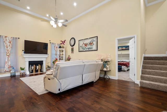 living area featuring crown molding, dark wood finished floors, stairway, and a fireplace with flush hearth