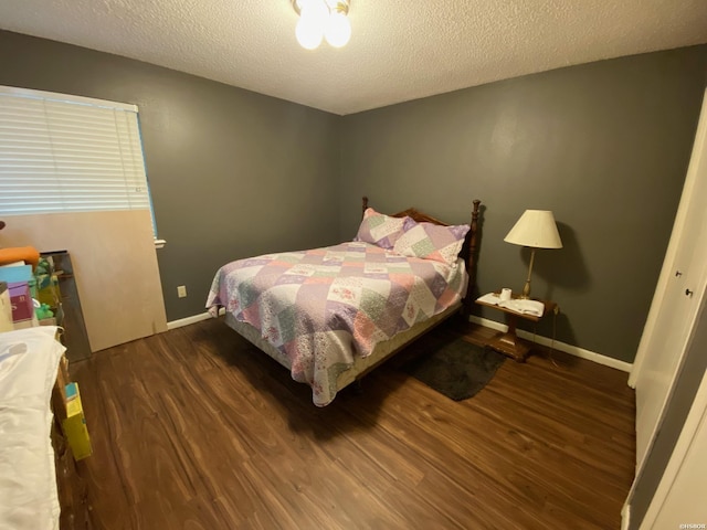 bedroom featuring dark wood finished floors, a textured ceiling, and baseboards