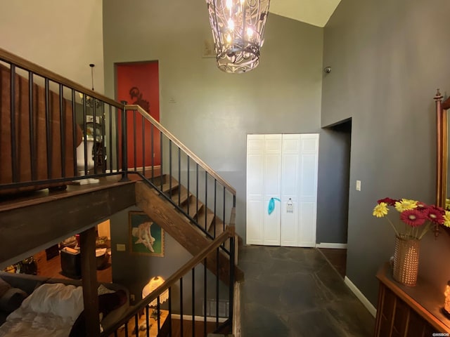 stairway featuring a towering ceiling, baseboards, and an inviting chandelier