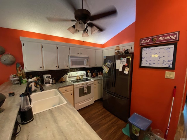 kitchen featuring lofted ceiling, white appliances, a sink, light countertops, and dark wood-style floors