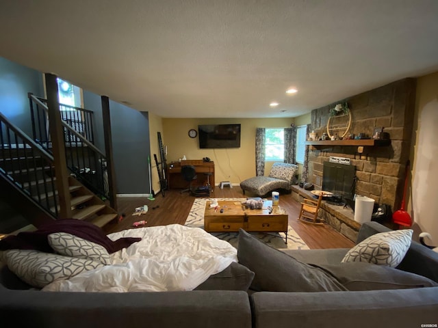 living area featuring a fireplace, stairway, wood finished floors, and recessed lighting