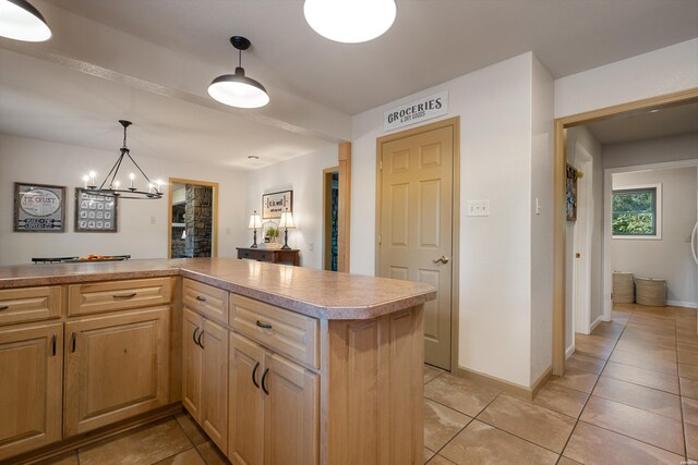 kitchen with light brown cabinetry, light tile patterned flooring, light countertops, and decorative light fixtures