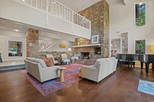 living area featuring a stone fireplace, wood finished floors, visible vents, and ornate columns