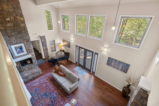 living area featuring a high ceiling, a fireplace, visible vents, french doors, and dark wood finished floors