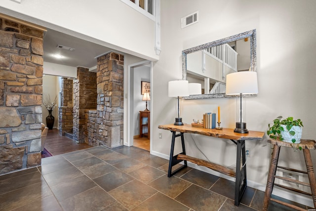 corridor featuring decorative columns, visible vents, and baseboards