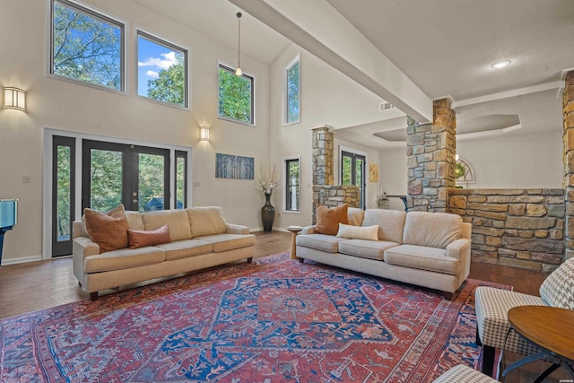 living area featuring french doors, decorative columns, a wealth of natural light, visible vents, and wood finished floors