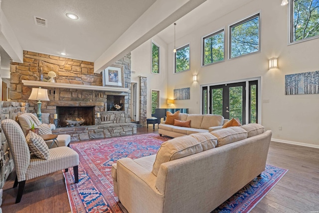 living room featuring french doors, visible vents, a stone fireplace, wood finished floors, and baseboards