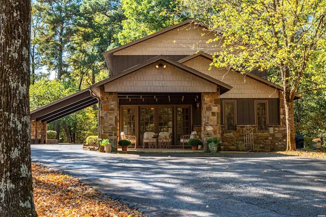 chalet / cabin with a carport, stone siding, and aphalt driveway