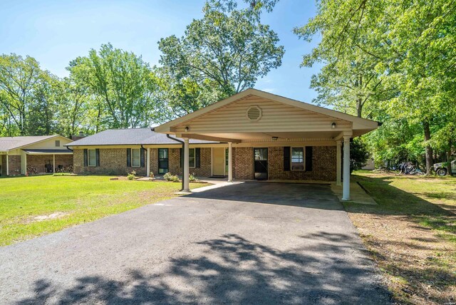 single story home featuring a carport, brick siding, driveway, and a front lawn