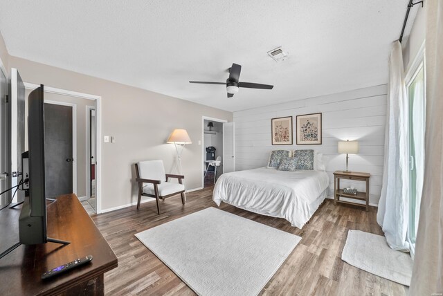 bedroom featuring visible vents, baseboards, ceiling fan, wood finished floors, and a textured ceiling