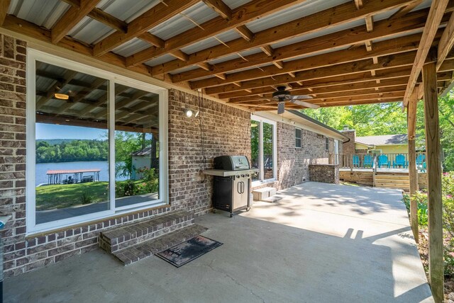 view of patio / terrace with a water view, grilling area, a ceiling fan, and entry steps