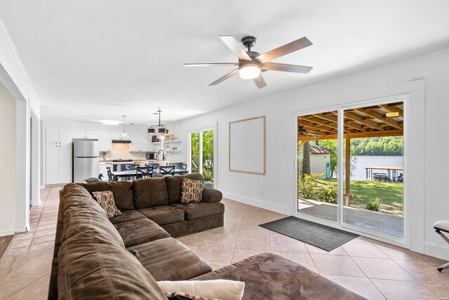 living room featuring a water view, ceiling fan, baseboards, and light tile patterned flooring