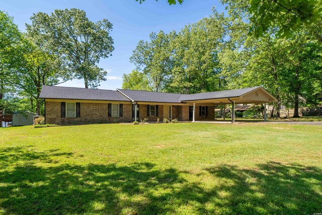 ranch-style home with a carport, a front yard, an outdoor structure, and a shed