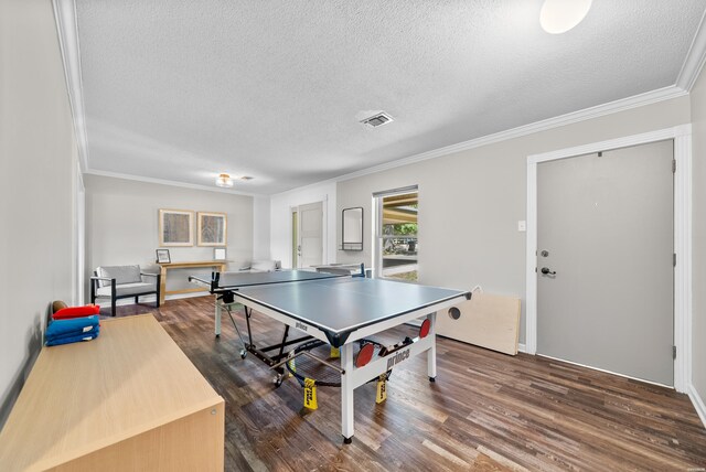 game room featuring visible vents, dark wood finished floors, a textured ceiling, and ornamental molding